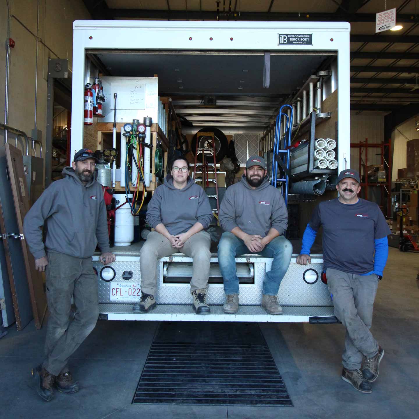 4 working posing for a photo in the back of an aries service van